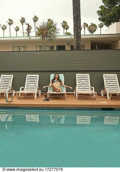 Frau entspannt auf Liegestuhl am Pool im Sommerurlaub