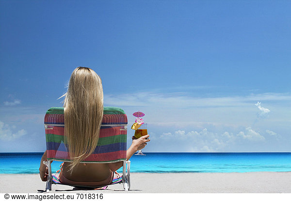 Frau entspannt im Liegestuhl am Strand