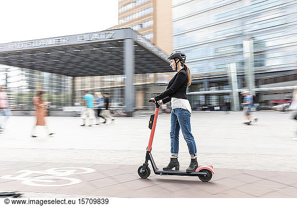 Frau fährt E-Scooter in der Stadt  Berlin  Deutschland  Berlin  Deutschland