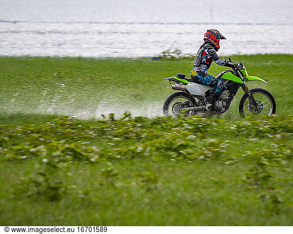 Frau fährt mit ihrem Geländemotorrad durch ein Feuchtgebiet bei Pak Chong / Thailand