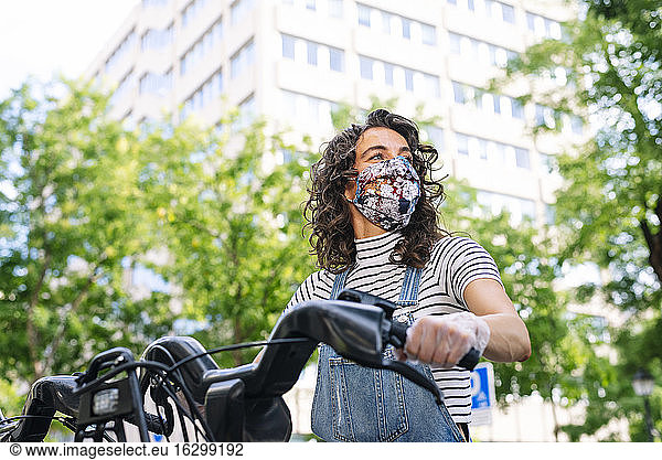 Frau fährt während der Coronavirus-Pandemie mit dem Elektrofahrrad durch die Stadt