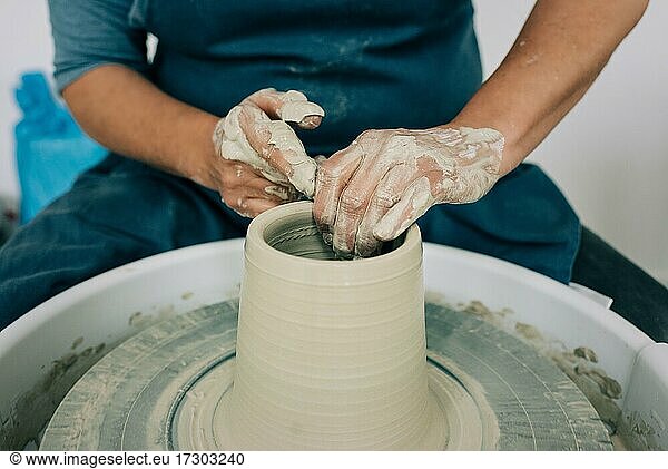 Frau formt Ton auf einer Töpferscheibe und stellt eine Vase her