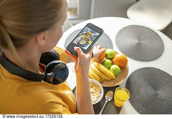 Frau fotografiert zu Hause Obst mit ihrem Smartphone