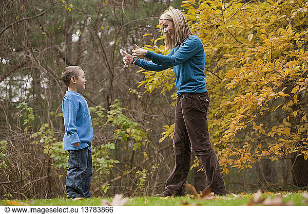 Frau gebärdet das Wort ´Play´ in amerikanischer Zeichensprache  während sie mit ihrem Sohn kommuniziert