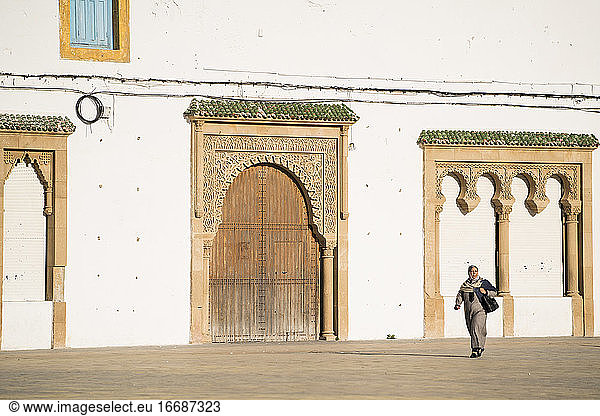 Frau geht an marokkanischer Festungsmauer vorbei