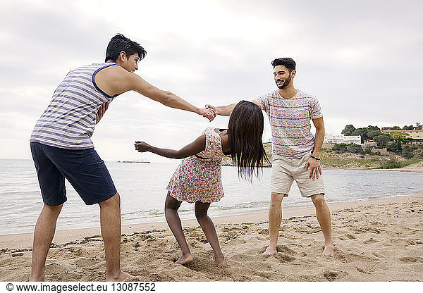 Frau geht beim Spielen am Strand unter den Armen der Männer vorbei