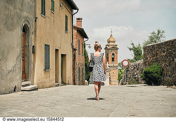 Frau geht entlang alter Straßen zur Kapelle