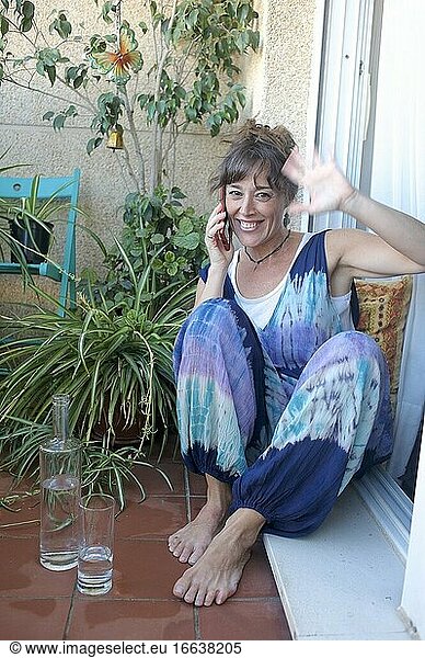 Frau genießt auf ihrer Terrasse und spricht am Telefon