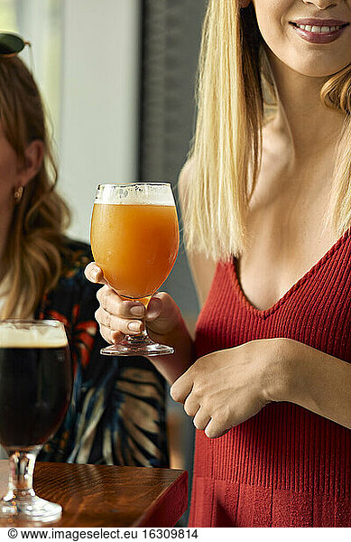 Frau hält ein Glas Craft Beer in einer Kneipe