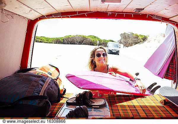 Frau hält Surfbrett im Kofferraum an einem sonnigen Tag