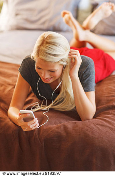 Frau hört mp3-Player auf dem Bett
