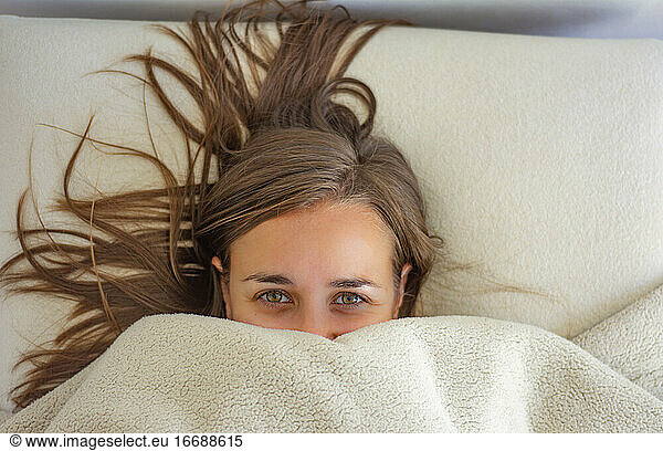 Frau im Bett bis zum Gesicht bedeckt
