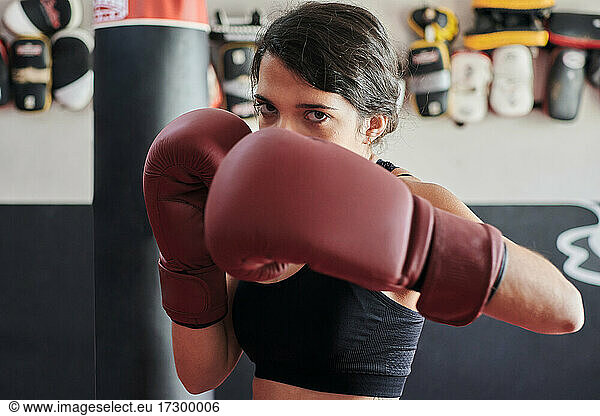 Frau in Boxhandschuhen trainiert mit Blick in die Kamera