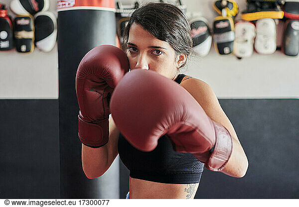 Frau in Boxhandschuhen trainiert mit Blick in die Kamera