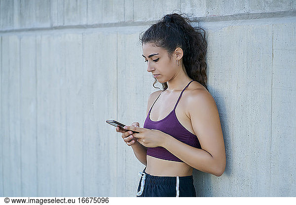 Frau in Sportkleidung schaut auf ein Smartphone