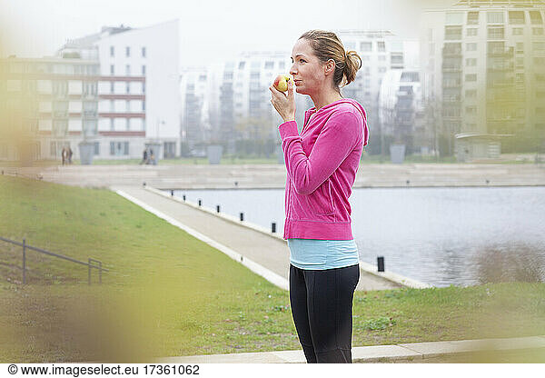 Frau isst Apfel  während sie in der Stadt steht