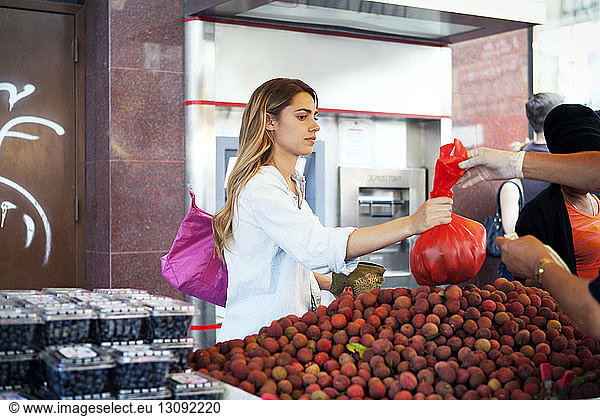 Frau kauft Früchte am Marktstand