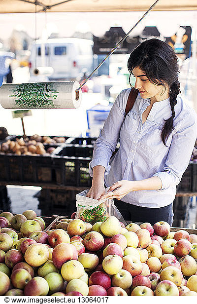 Frau kauft Äpfel am Marktstand