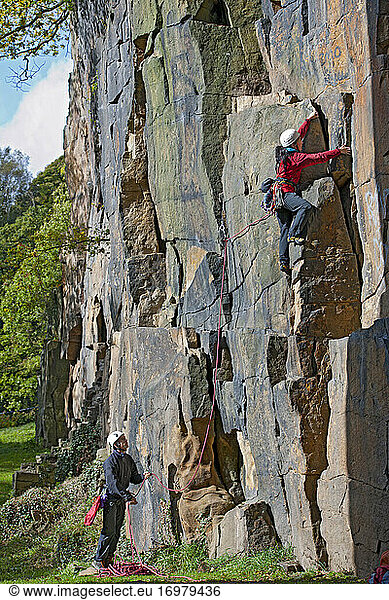 Frau klettert an steiler Felswand im Vereinigten Königreich