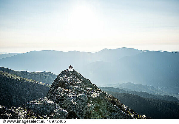 Frau klettert morgens in den Bergen über den Gipfel