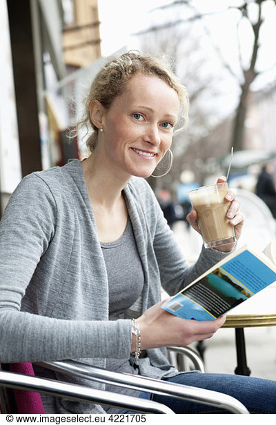 Frau liest Buch im Kaffeehaus