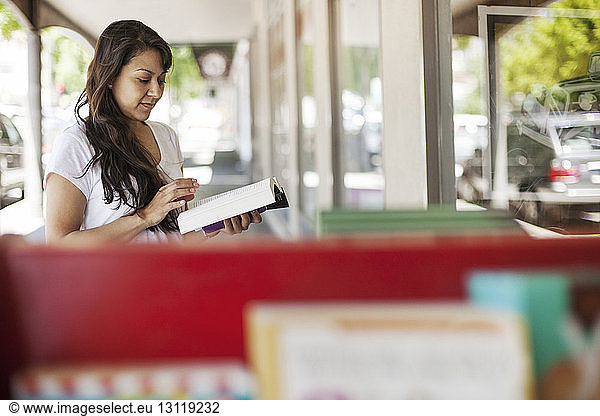 Frau liest Buch im Laden