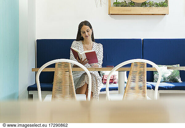 Frau liest Buch im Restaurant