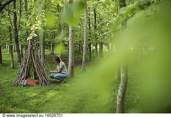 Frau macht Ast-Tipi im Wald