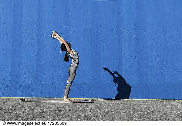 Frau macht Übung auf Matte gegen blaue Wand