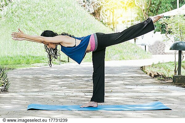 Frau macht Krieger III Yoga im Freien  Mädchen macht Virabhadrana III Yoga  junge Frau macht Yoga im Freien  Krieger III Yoga Konzept