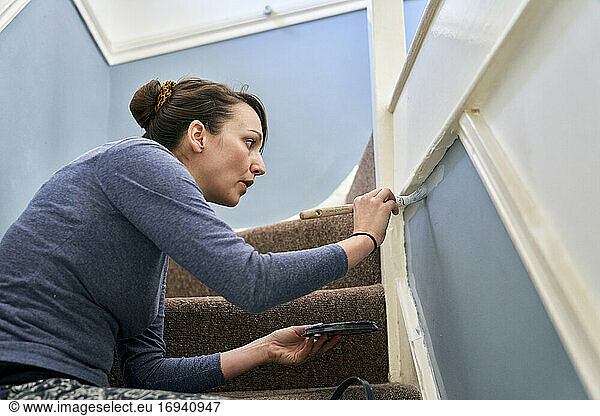Frau malt Treppe zu Hause