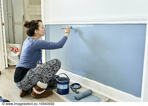 Frau malt Wand zu Hause.