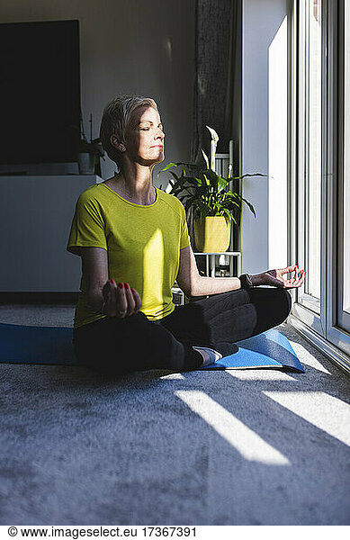 Frau meditiert im Lotussitz zu Hause