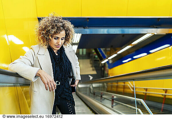 Frau mit Afro-Haar  die die Rolltreppe hochfährt