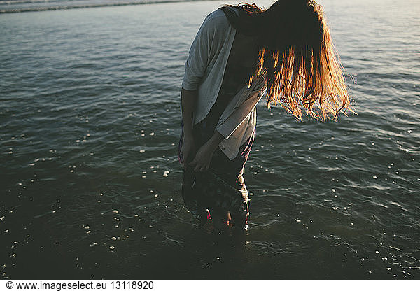 Frau mit braunen Haaren steht im Meer
