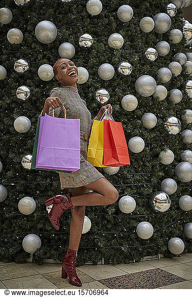 Frau mit bunten Einkaufstaschen auf einem Weihnachtsbaum