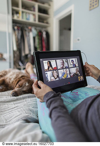 Frau mit digitalem Tablet Video-Chat mit Freunden im Bett mit Hund