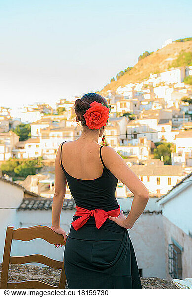 Frau mit einer Rose im Haar blickt auf ein spanisches Dorf