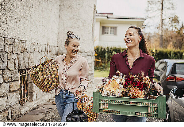 Frau mit Freundin trägt Blumenkiste