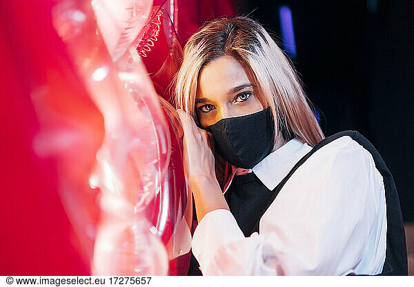 Frau mit Gesichtsschutzmaske steht vor rotem Licht