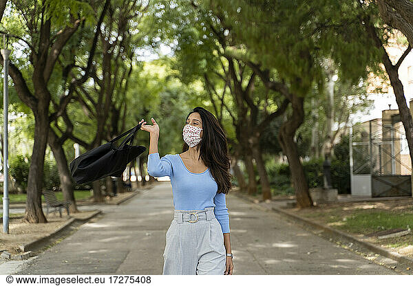 Frau mit Handtasche auf dem Fußweg im Park während COVID-19