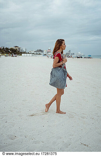 Frau mit Handtasche auf Sand am Strand