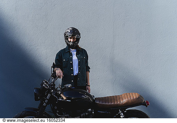 Frau mit Helm am Motorrad stehend