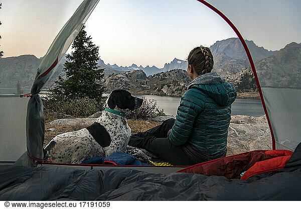 Frau mit Hund beim Zelt sitzend beim Camping im Urlaub