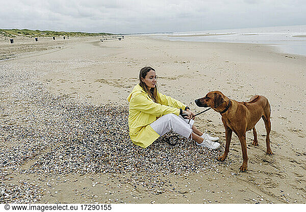 Frau mit Hund verbringt ihre Freizeit am Strand