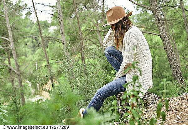 Frau mit Hut  sitzend im Wald