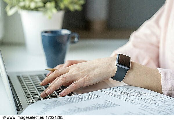 Frau mit intelligenter Uhr benutzt Laptop zu Hause
