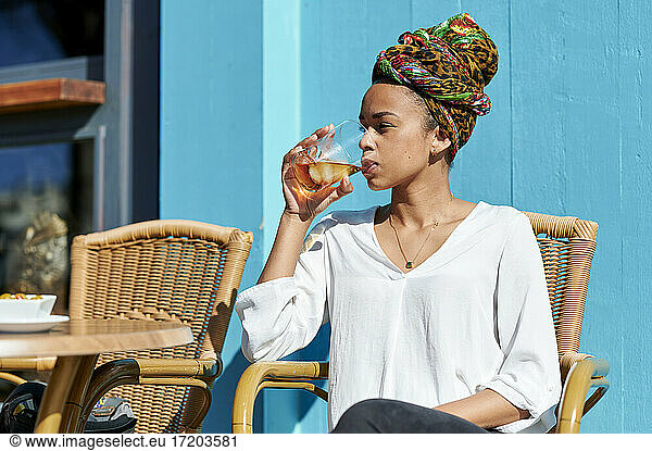 Frau mit Kopftuch trinkt Alkohol  während sie an einer Bar sitzt