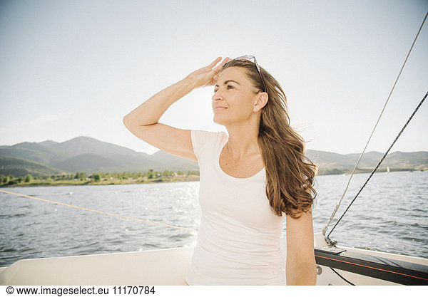 Frau mit langen braunen Haaren auf einem Segelboot stehend.