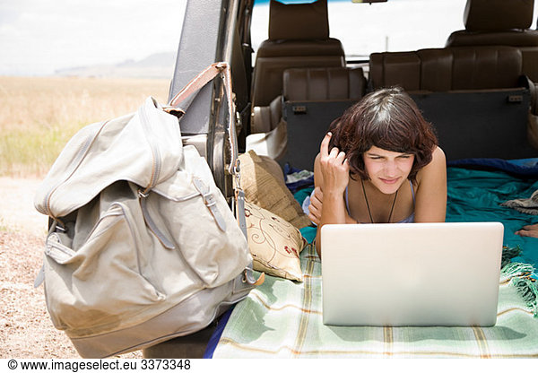 Frau mit Laptop im Fahrzeug
